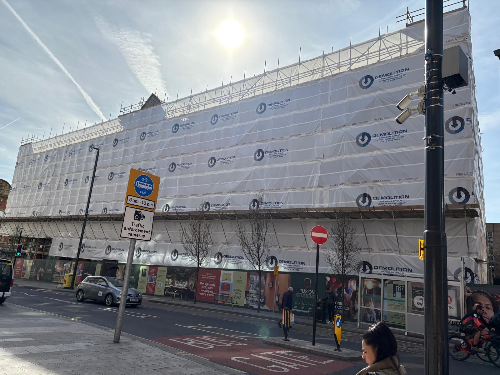 White printed scaffold wrap covering a street-front demolition site