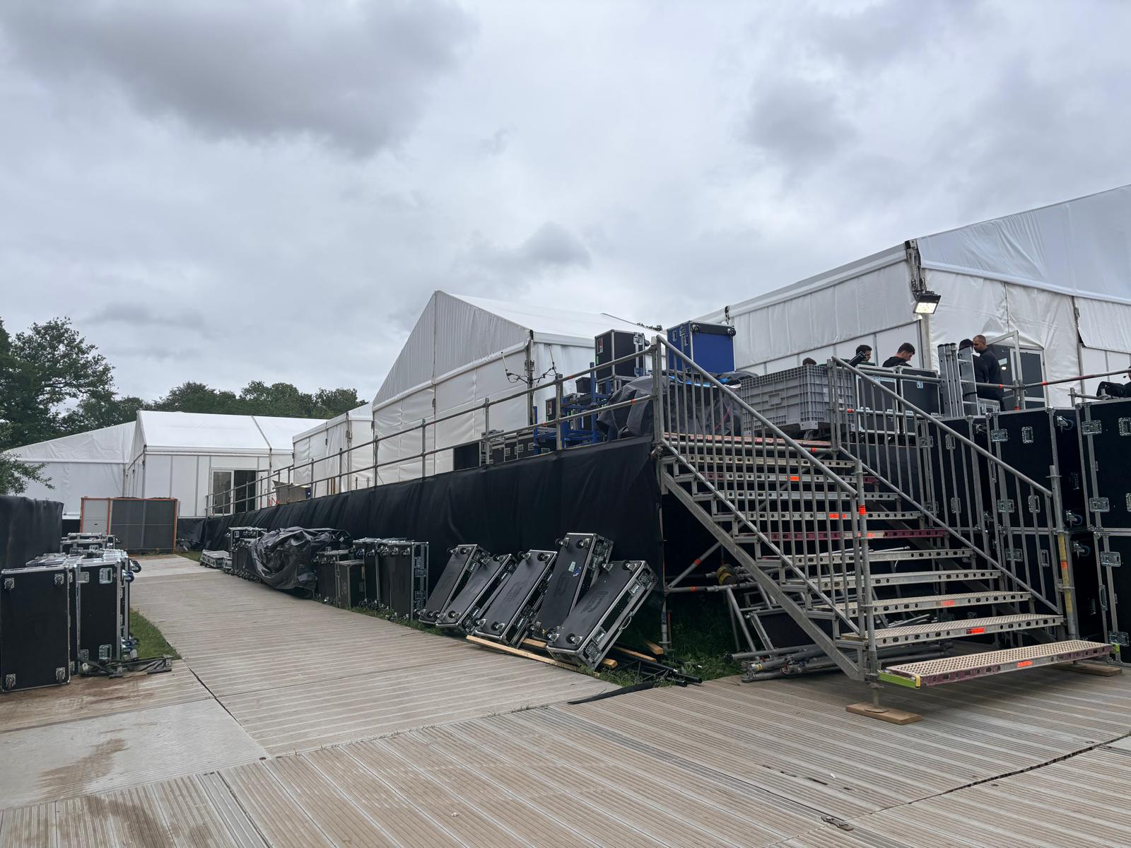 Scaffold staircase onto a raised platform beside white event marquees