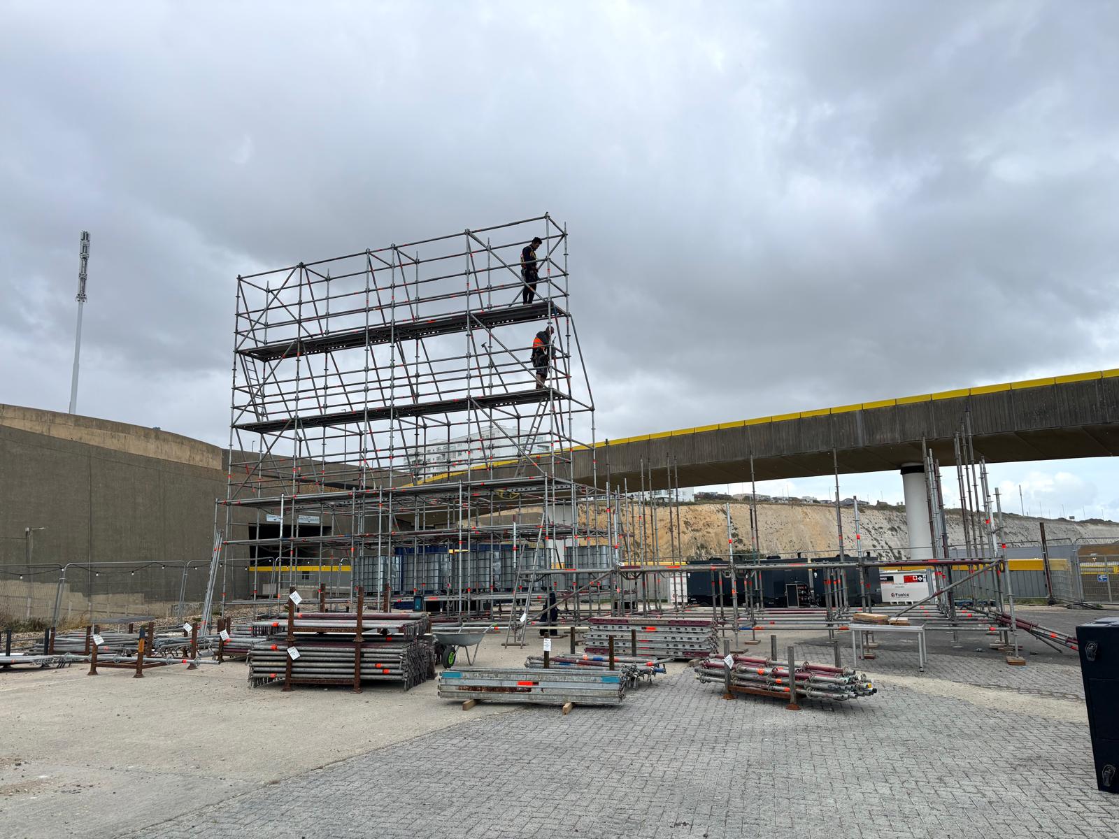 Crew building a multi-lift galvanised scaffold tower on a UK infrastructure site